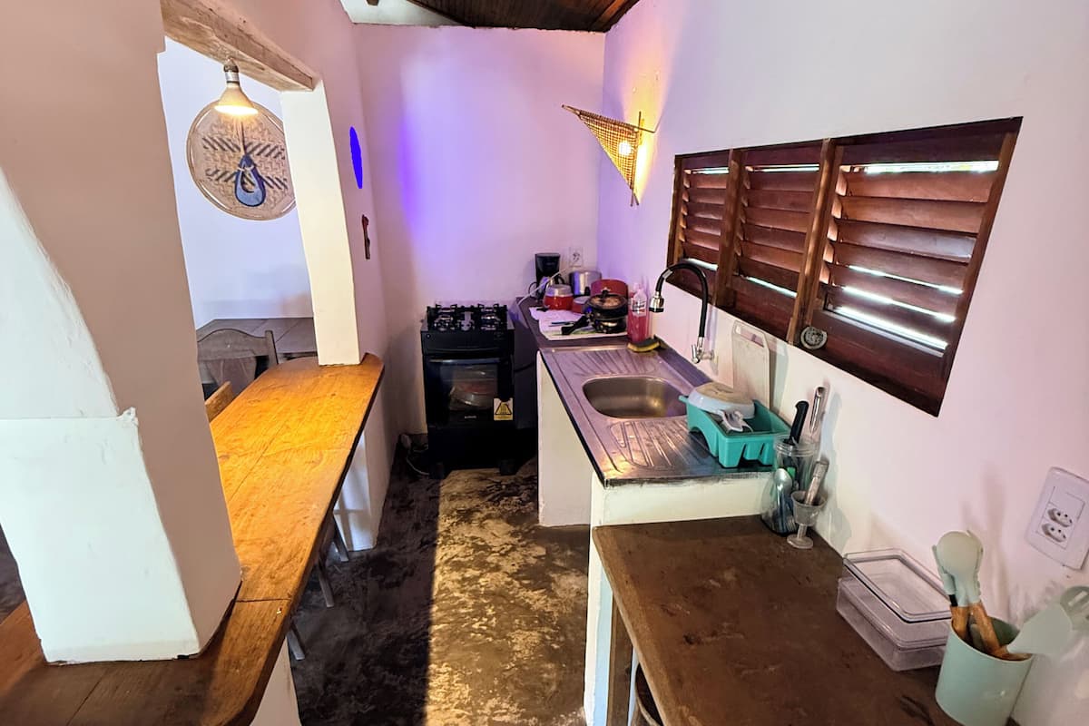 A compact kitchen with a gas stove, sink, and wooden ceiling.