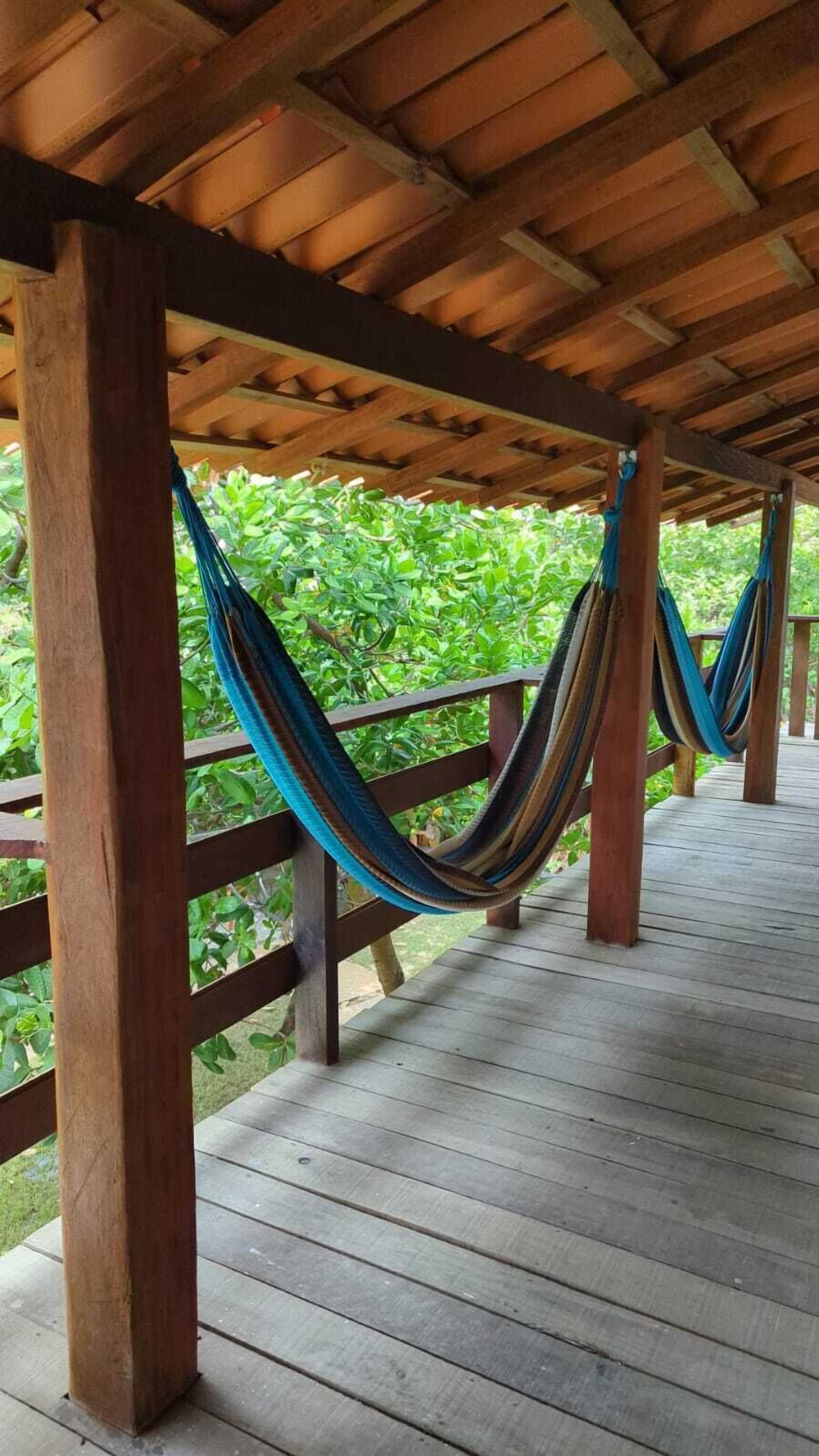 Une terrasse en bois avec un hamac et une rambarde en bois.