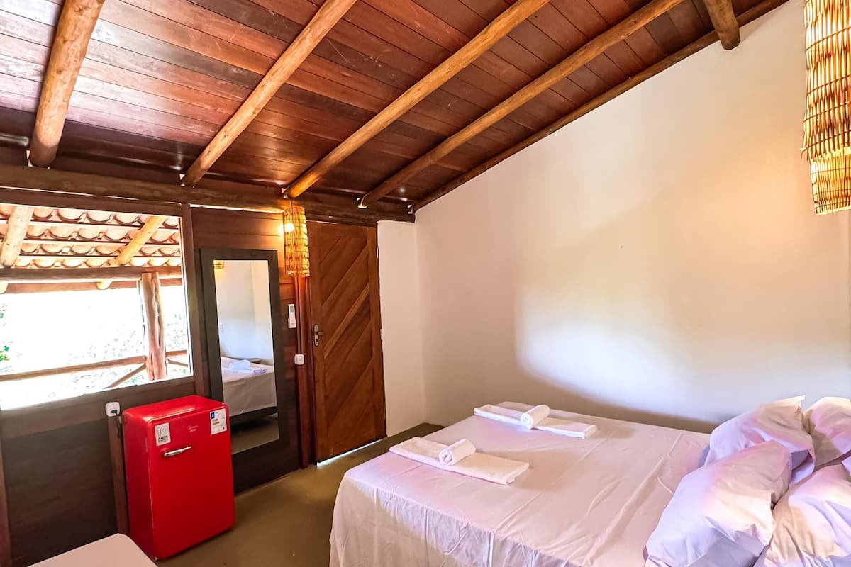A room with two beds, a red refrigerator, and a woven ceiling light fixture.