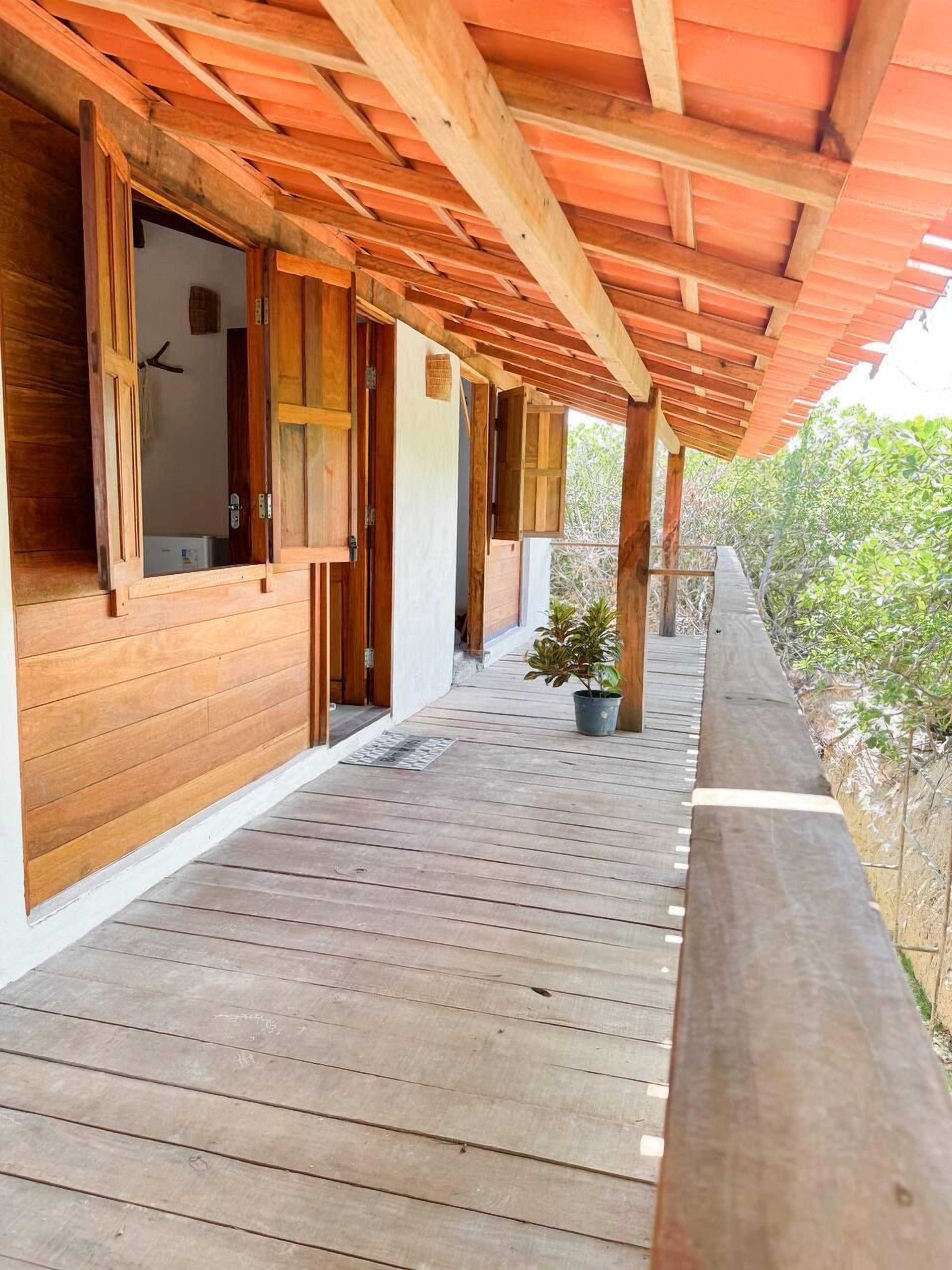 Una terraza de madera con un área cubierta, paredes de madera y una planta en maceta.