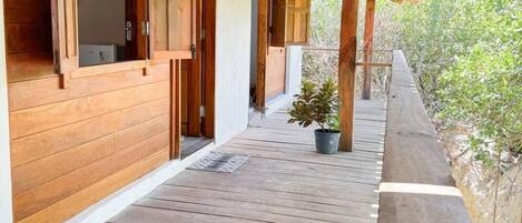 Una terraza de madera con un área cubierta, paredes de madera y una planta en maceta.