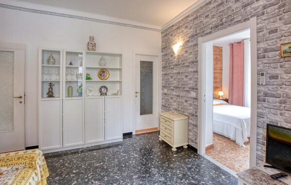 Habitación de hotel con cama, televisor, armario y baño visible a través de una puerta abierta.