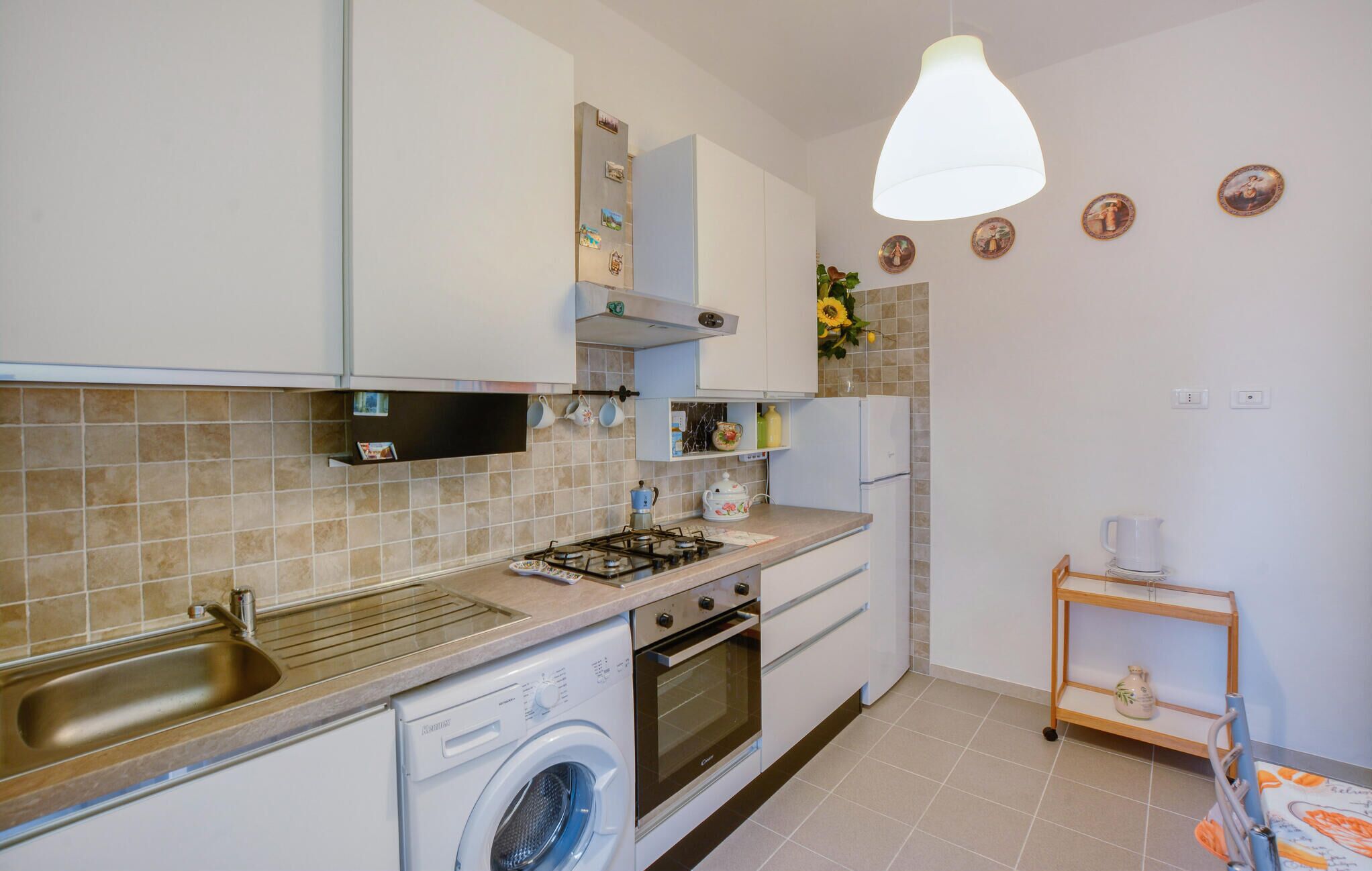 A compact kitchen with a washing machine, oven, and sink.