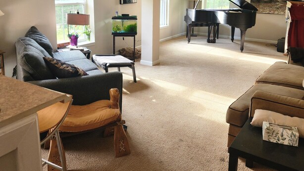 A spacious living room with a grand piano, a comfortable sofa, and a small table.