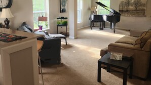 A spacious living room with a grand piano, a cozy sofa, and a coffee table.