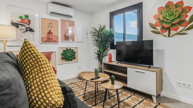 Una sala de estar moderna con un sofá, televisión, una mesita y obras de arte en las paredes.