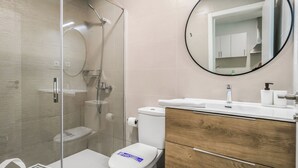 Une salle de bain moderne avec une douche à parois de verre, des toilettes, un lavabo avec un miroir et des meubles en bois.