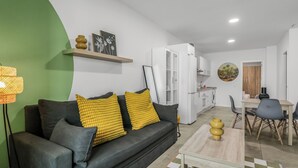 Un salon moderne avec un canapé noir, des coussins jaunes, une table basse en bois et un tapis à carreaux.