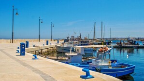 A marina with boats docked, a paved walkway, and street lamps. - Lovely home in Marzamemi with WiFi (Marzamemi)