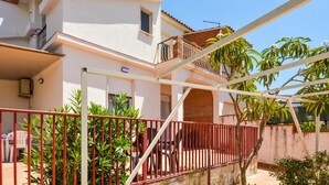 A two-story house with a balcony, a red metal fence, and potted plants. - Lovely home in Marzamemi with WiFi (Marzamemi)
