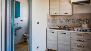 A compact kitchen with a sink, stove, and cabinets. - Lovely home in Marzamemi with WiFi (Marzamemi)