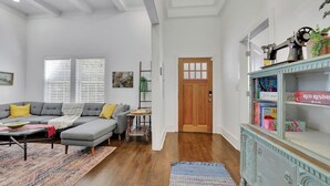 A living room with a grey sofa, a small table, and a bookshelf. - Charming 3BR Retreat - Spacious Deck, Backyard (Atlanta)