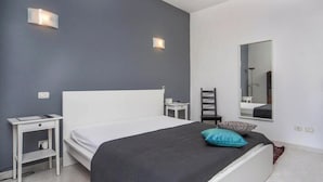 Une chambre à coucher avec un lit, une table de chevet, une chaise et un miroir.