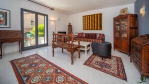 Un salon avec un banc en bois, un canapé, une armoire et un tapis.