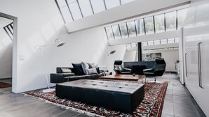 Een moderne woonkamer met een bank, twee fauteuils, een salontafel en een kamerkleed met dessin.