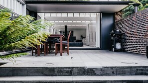 Un patio al aire libre con una mesa de comedor y sillas, un muro de ladrillo y una estufa a gas.