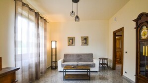 Ein Wohnzimmer mit Sofa, Couchtisch, Stehlampe und zwei gerahmten Bildern an der Wand.