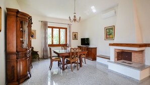 Ein Essbereich mit Holztisch und -stühlen, einer Chandelüster, einem Kamin und einem Fernseher.