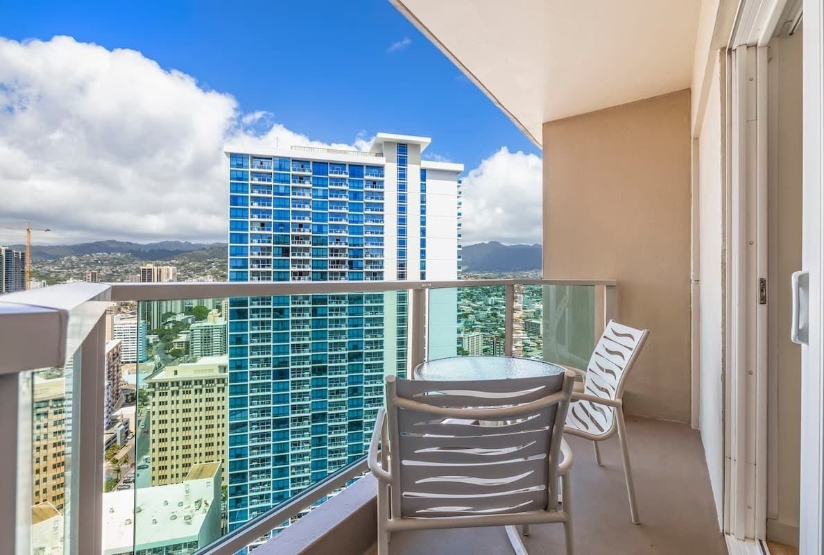 Un balcon donnant sur un grand immeuble bleu, avec une chaise et une table.