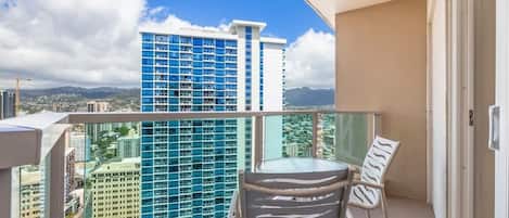Un balcon donnant sur un grand immeuble bleu, avec une chaise et une table.