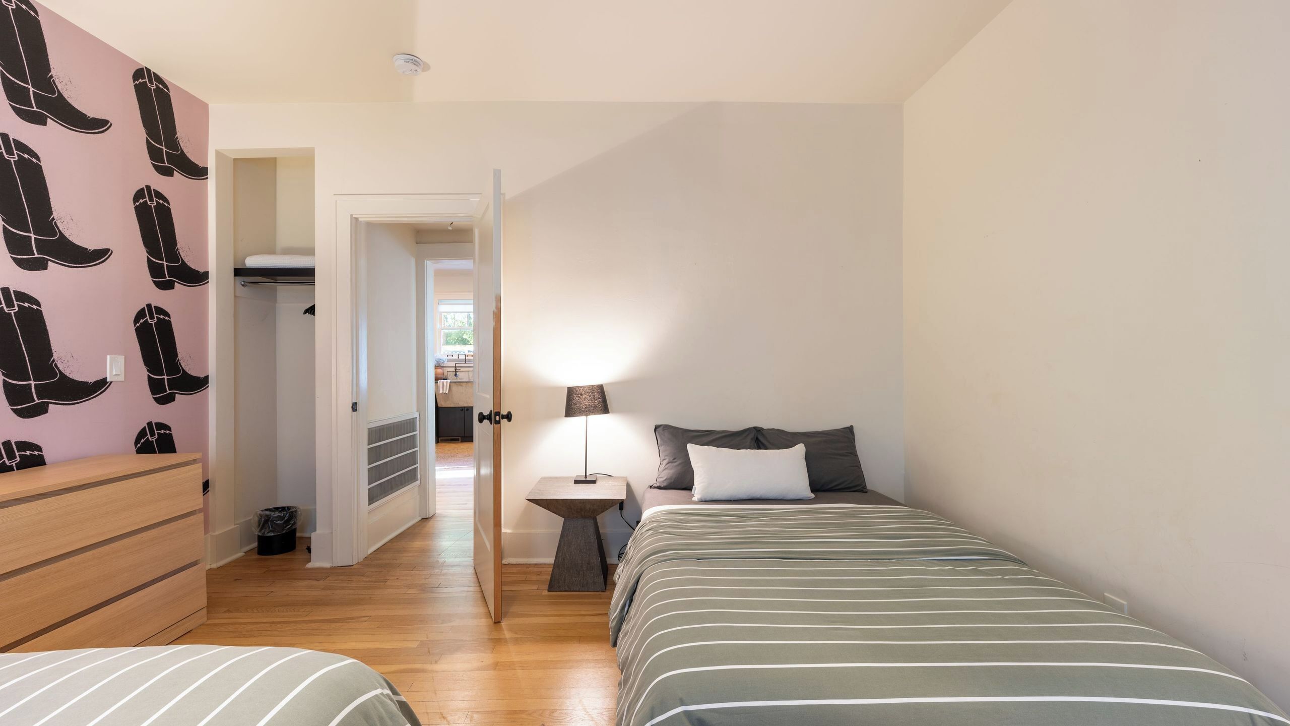 A bedroom with a bed, bedside table, lamp, and a wardrobe.