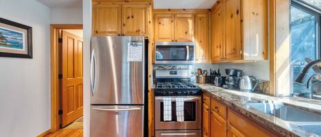A kitchen with wooden cabinets, stainless steel appliances, and a granite countertop.