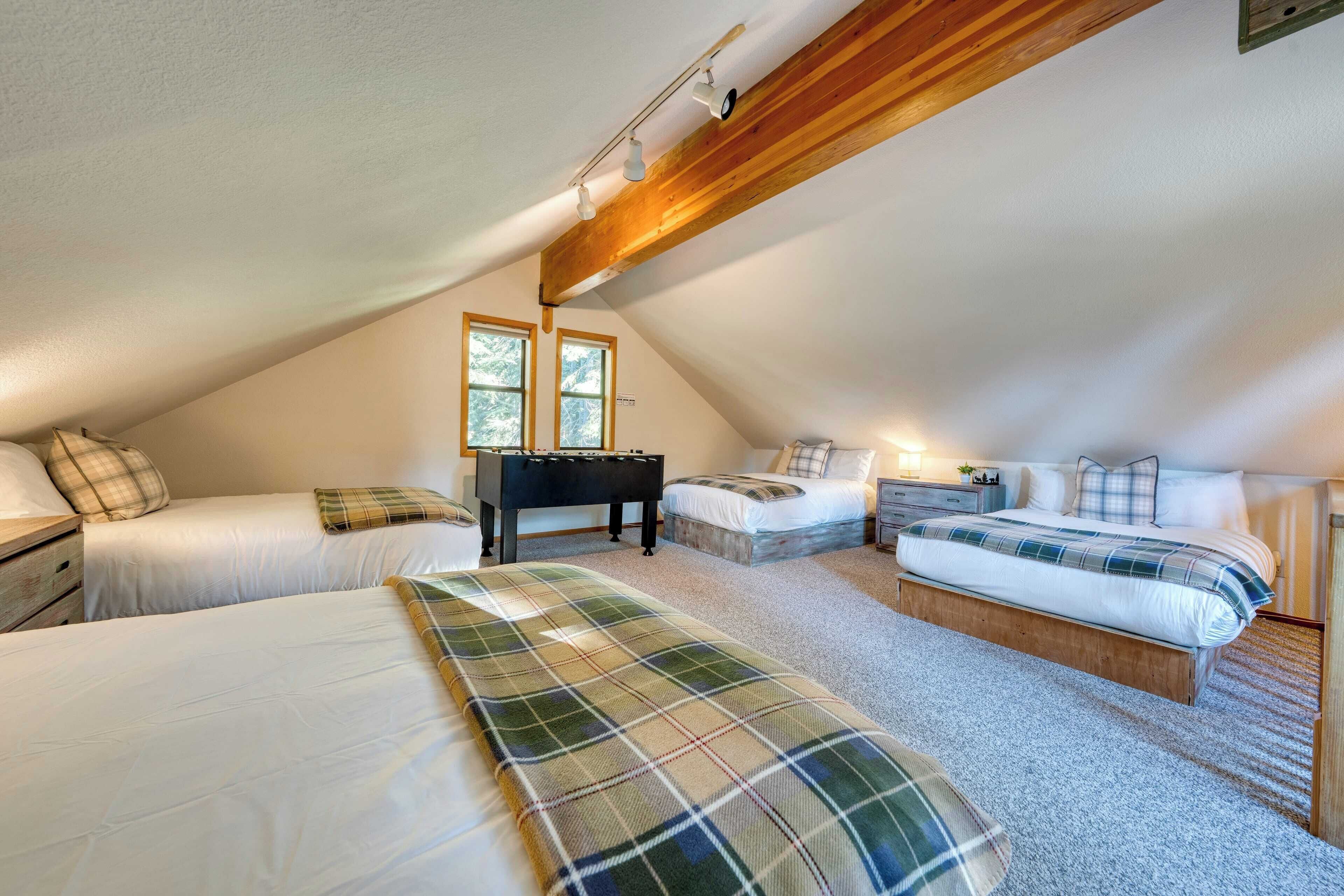 Een gezellige slaapkamer onder het dak met twee bedden, een tafelvoetbaltafel en een schuine plafond met zichtbare balken.