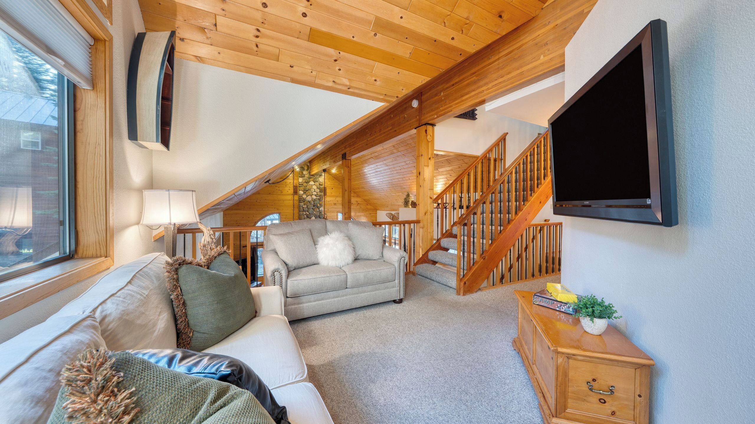 Un salon confortable avec un canapé, une lampe, un téléviseur et un escalier menant à un étage supérieur.
