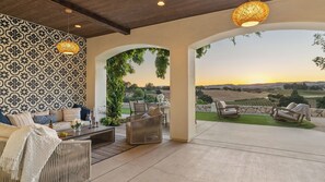 A patio with outdoor seating, a patterned wall, and a view of the countryside. - Wine Country Escape w/ Views + Wine Cellar & Gym Caterina Dusi Vineyard by Avantstay (Paso Robles)