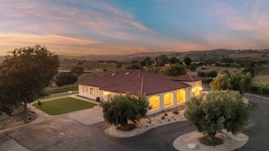 A two-story house with a red-tiled roof, surrounded by a well-maintained lawn and several trees. - Wine Country Escape w/ Views + Wine Cellar & Gym Caterina Dusi Vineyard by Avantstay (Paso Robles)