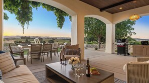 An outdoor patio with a table set for dining, a sofa, and a grill area.
