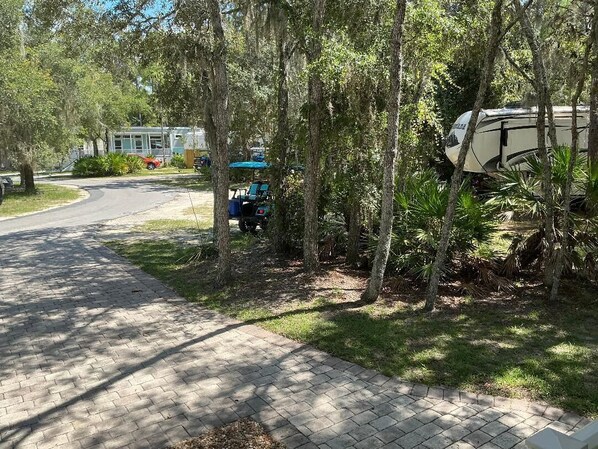 A paved pathway leading to a campground with RVs and a golf cart.