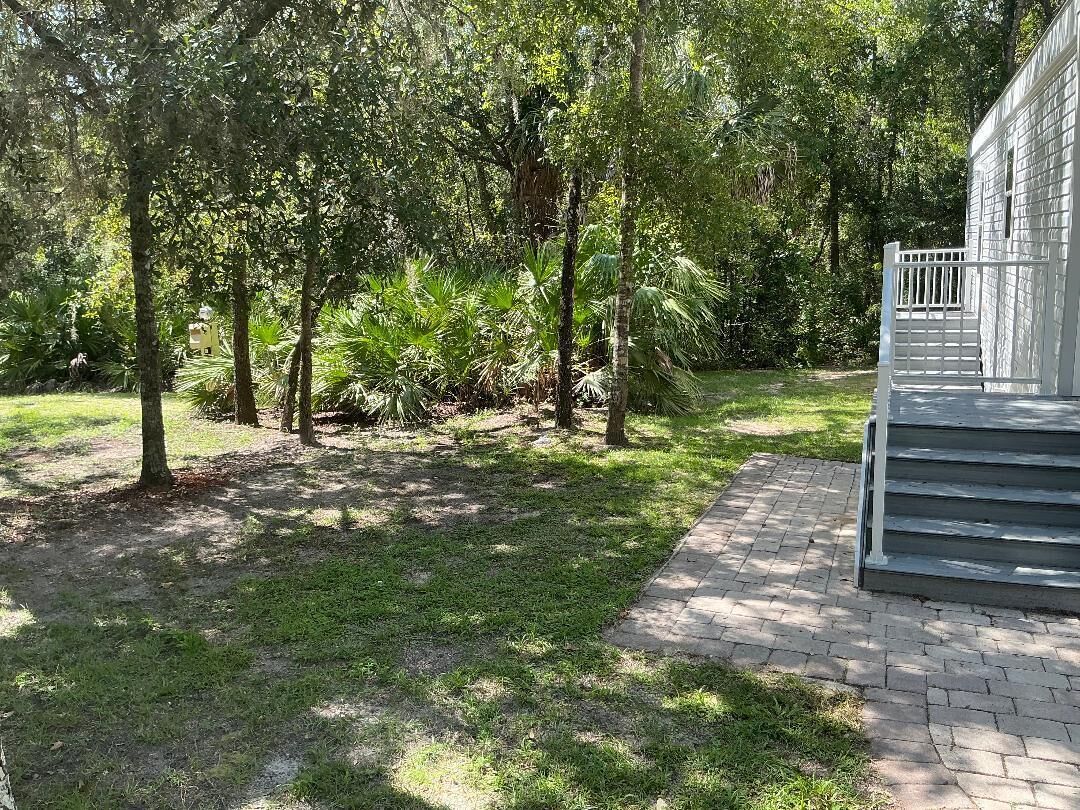A paved pathway leading to a building with a white exterior and a set of stairs.