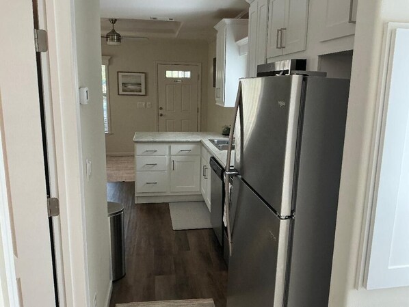 A compact kitchen with white cabinets, a stainless steel refrigerator, and a small countertop.
