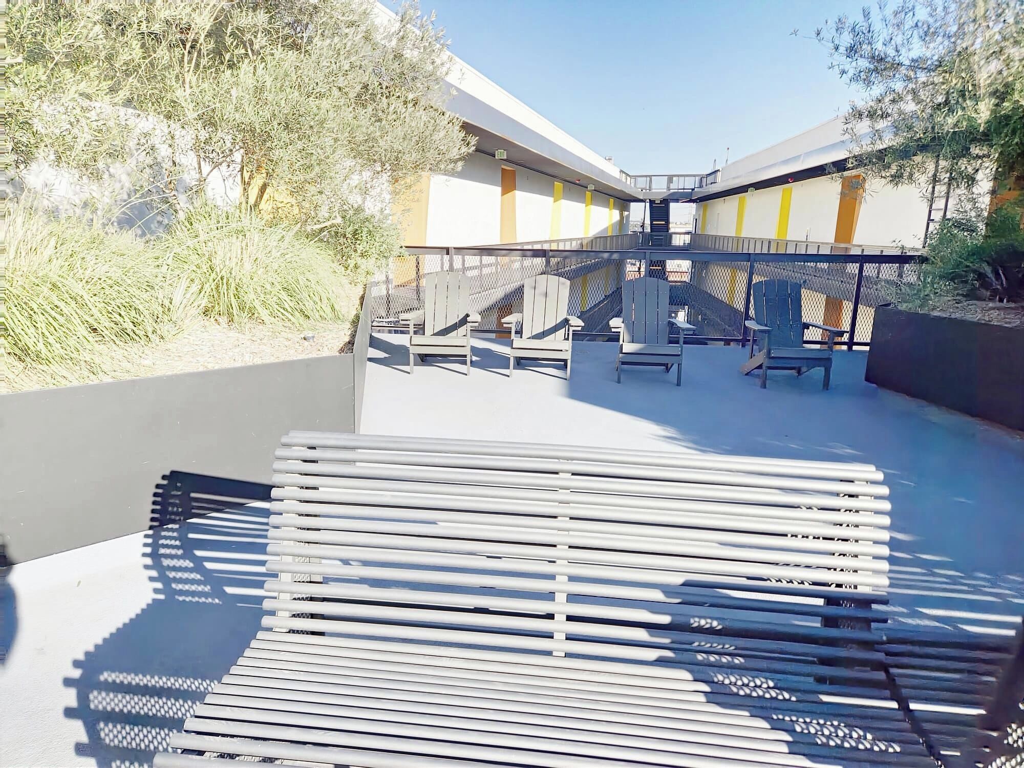 An outdoor seating area with chairs and tables, a staircase, and a building with yellow and white walls.