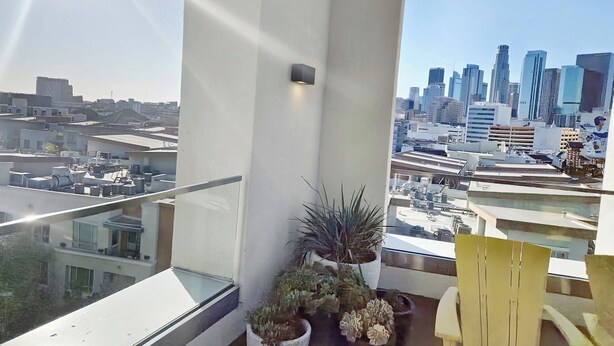 A balcony with a city view, potted plants, and a yellow chair.