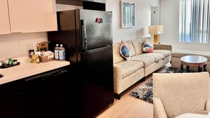 A modern kitchen with a black refrigerator, a beige sofa, and a round coffee table.