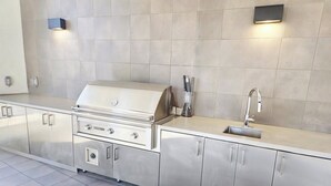 A modern kitchen with a stainless steel grill, a sink, and a tiled backsplash.
