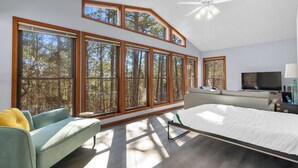 A modern bedroom with large windows, a bed, a sofa, and a television. - Stay and Play HSV (Hot Springs)