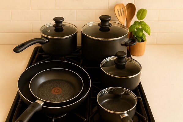 Una cocina con estufa a gas, una sartén, dos ollas y una pequeña planta en maceta.