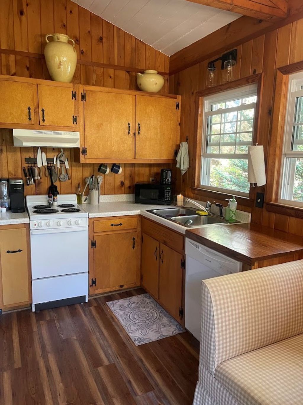 A compact kitchen with wooden cabinets, a stove, a microwave, and a sink.