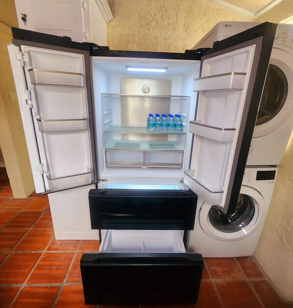 Un refrigerador compacto con un cajón congelador, un dispensador de agua y una lavadora integrada.