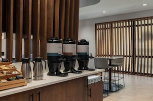 Una estación de café moderna con varios dispensadores, un hervidor y una cafetera.