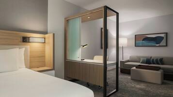 A hotel room with a bed, a desk with a chair, a sofa, and a large mirror.