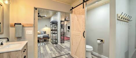 A modern bathroom with a wooden floor, a large mirror, a sink, and a toilet.