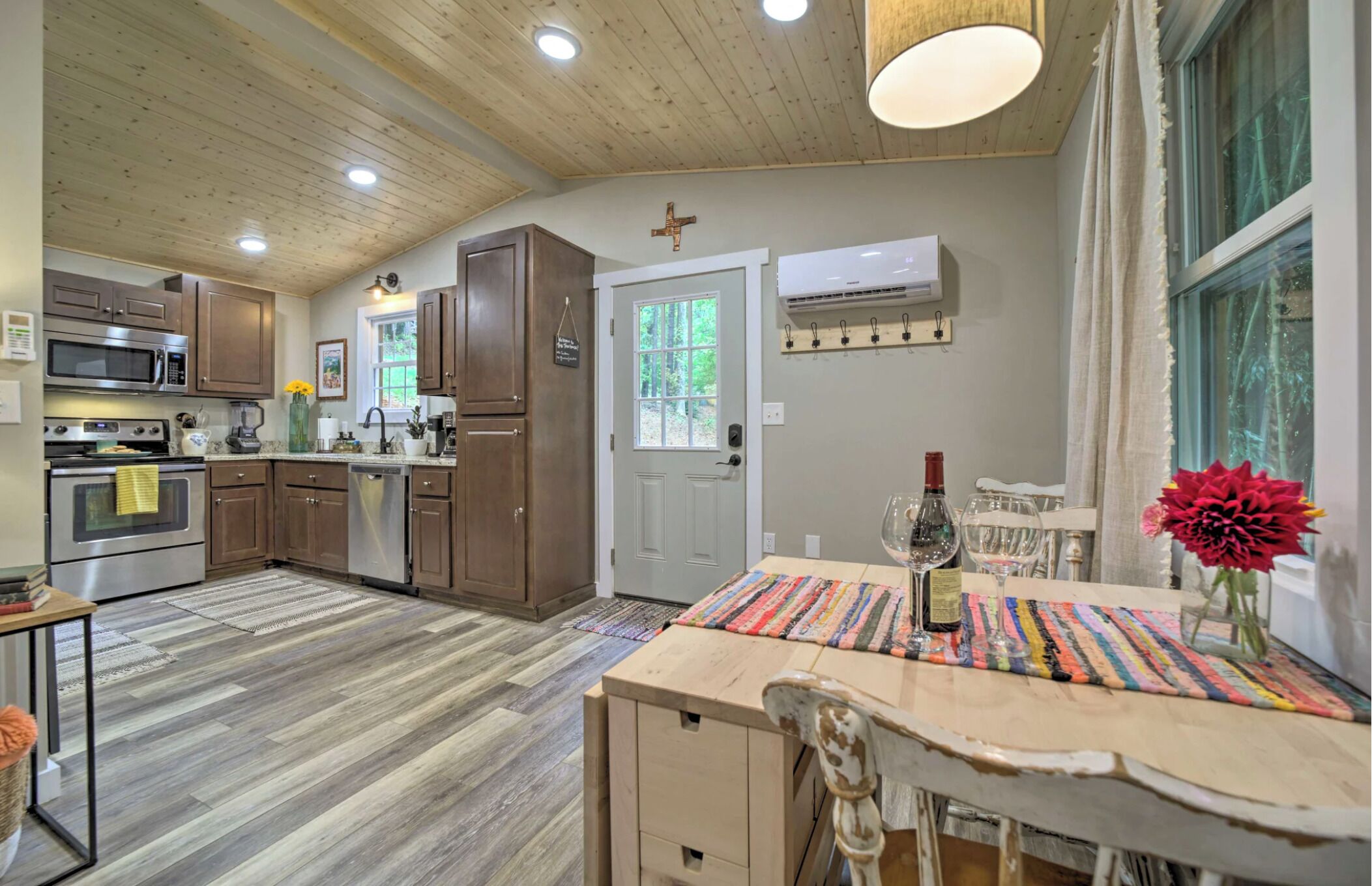 A kitchen with wooden cabinets, a microwave, an oven, and a dining area with a table and chairs.