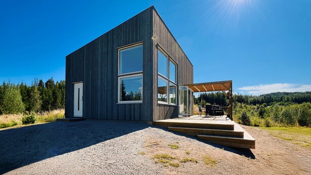 Een modern, gelijkvloers huis met grote ramen en een houten terras.