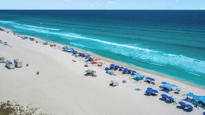 A beach with umbrellas and beach chairs, a sandy shore, and the ocean.