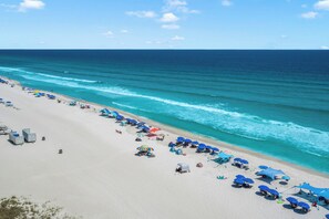 A beach with umbrellas and beach chairs, a sandy shore, and the ocean.