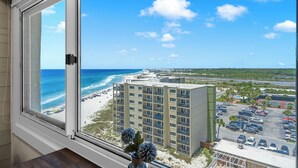 Vista dalla finestra su una spiaggia, un parcheggio e l'edificio di un hotel.